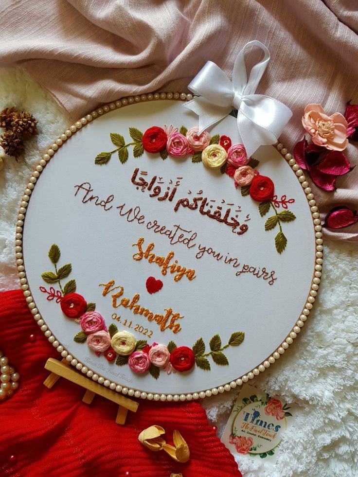 a white embroidered sign with flowers and words on it, surrounded by other items such as beads