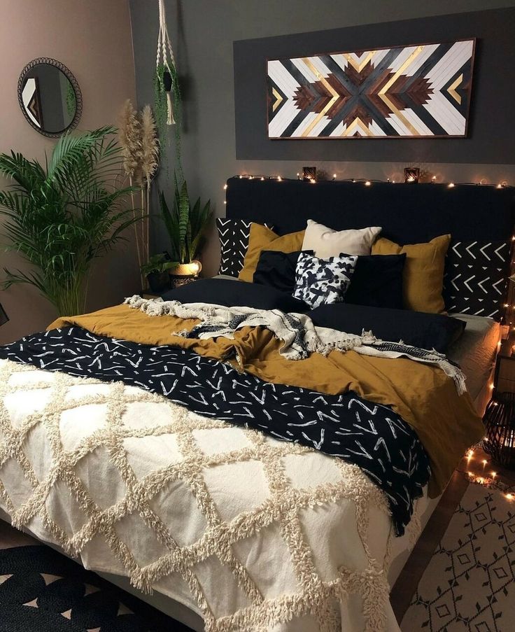 a bedroom decorated in black, white and gold with lights on the wall above the bed