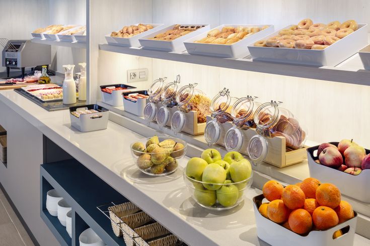 an assortment of fruits and pastries are on display in the breakfast buffet at this hotel