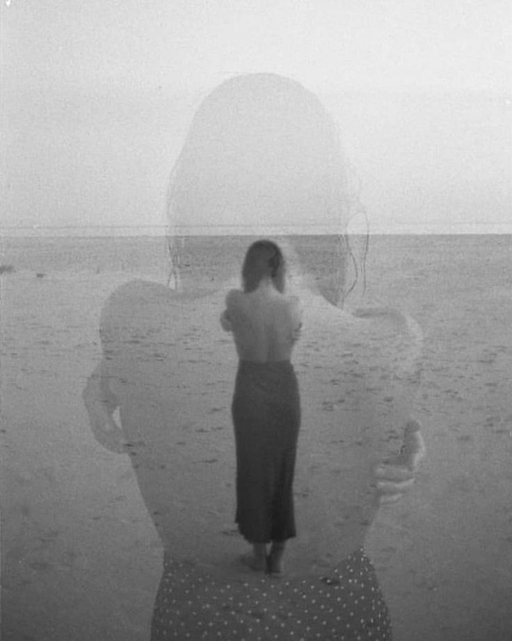 a woman standing on top of a beach next to the ocean with her back turned