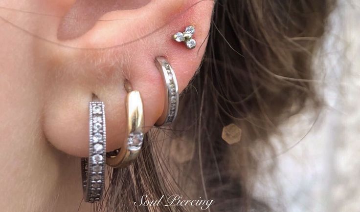 a woman wearing three different types of ear piercings