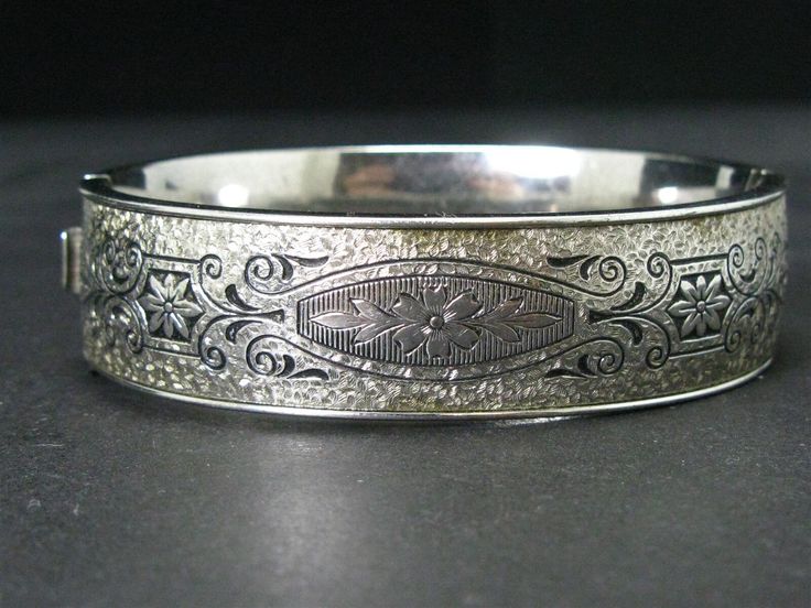 Cute early to mid 1900's bangle with engraved floral designs around it. 15mm tall face. Stamped sterling. Fits an approximate 7" wrist. Luxury Antique Engraved Sterling Silver Bracelet, Formal Engraved White Gold Bangle, Antique Cuff Bracelet With Intricate Design For Formal Occasions, Hallmarked Vintage White Gold Bangle, Vintage Hallmarked White Gold Bangle, Victorian Etched Cuff Bracelet, Victorian Etched Cuff Bracelet For Wedding, Antique Round Cuff Bracelet For Wedding, Victorian Silver Engraved Bangle