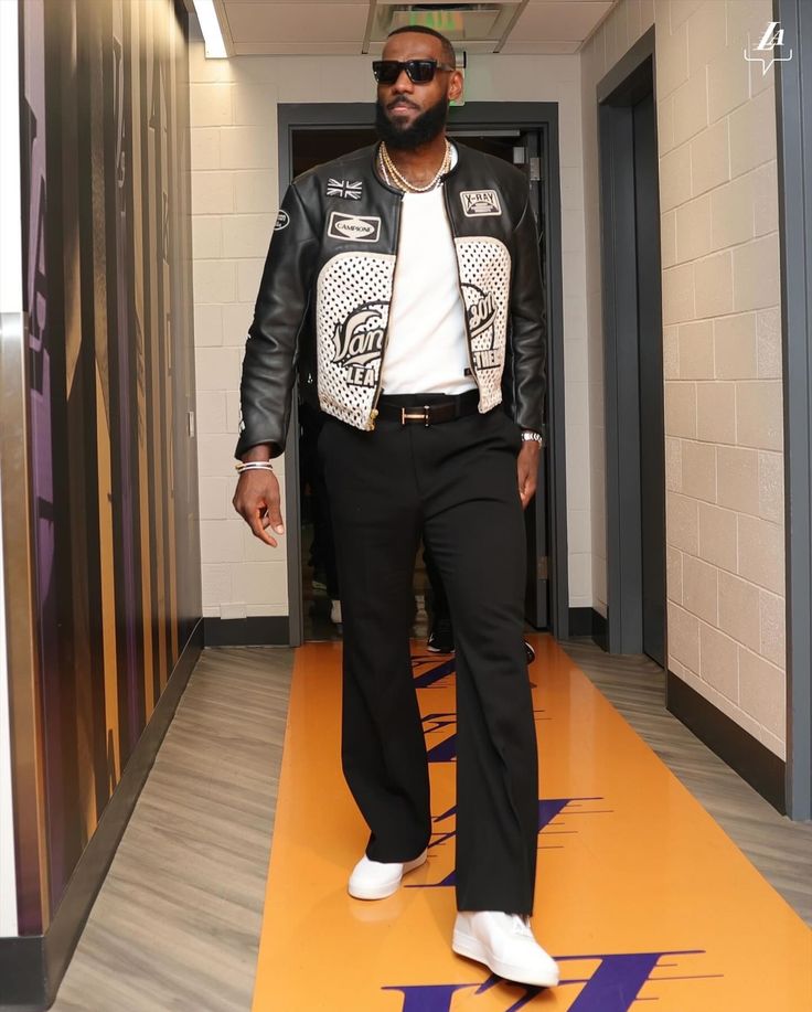 a man in black and white jacket walking down a hallway