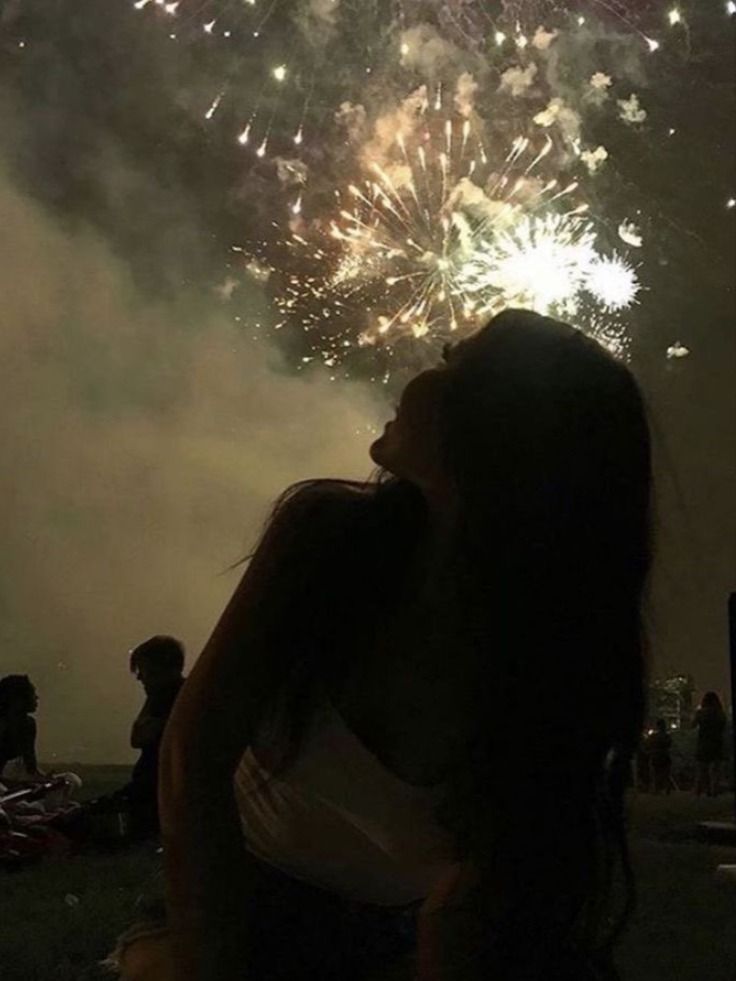 a woman is looking at fireworks in the sky