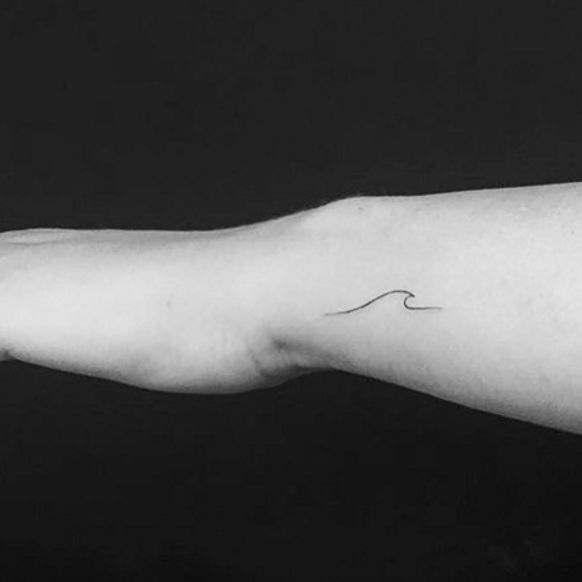 a black and white photo of a person's arm with a wave tattoo on it