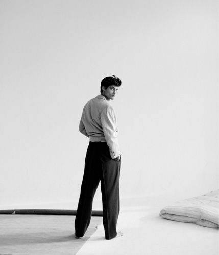 a man standing on top of a bed in front of a white wall with his back to the camera