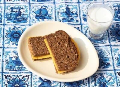 two pieces of bread on a plate next to a glass of milk and blue tile