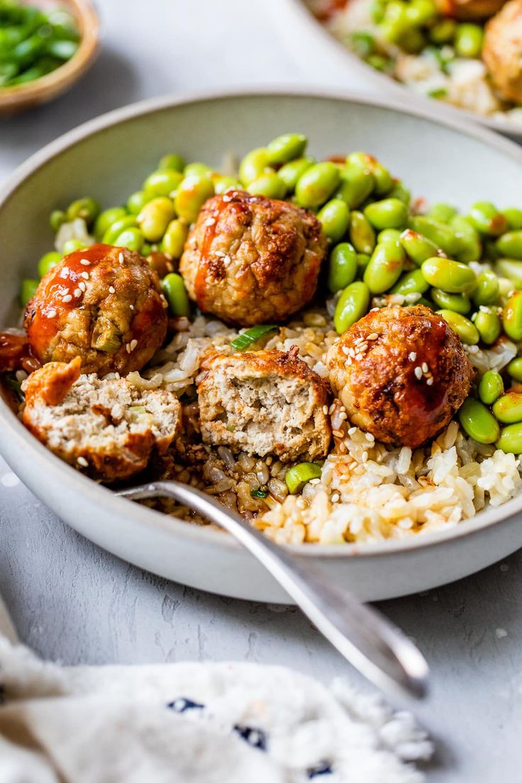 a bowl filled with meatballs, peas and rice