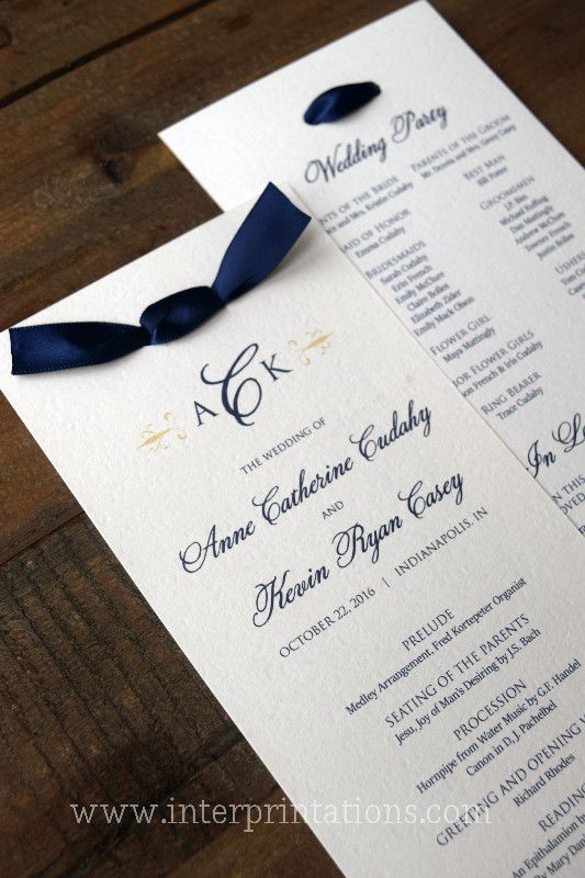 two wedding program cards with blue ribbon on wooden table top, ready to be used for ceremony