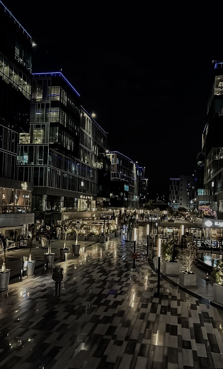 the city is lit up at night with people walking around