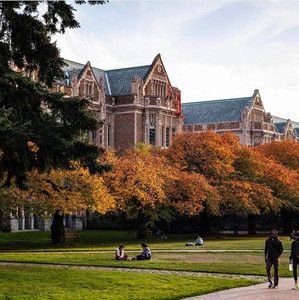 two people walking in front of a large building with lots of trees on both sides