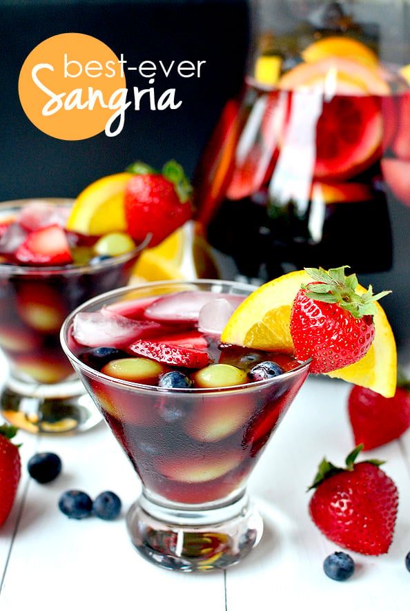 two glasses filled with sanggraa and fruit on a table next to sliced strawberries