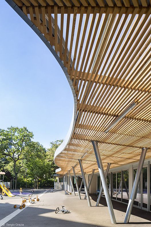 a large wooden structure sitting on the side of a road next to a building with lots of windows