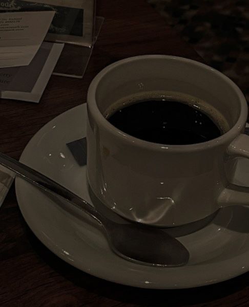 a cup of coffee sitting on top of a white saucer next to a spoon