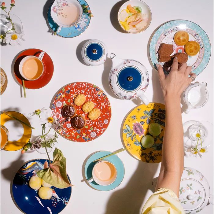 a table topped with plates and cups filled with desserts next to teacups