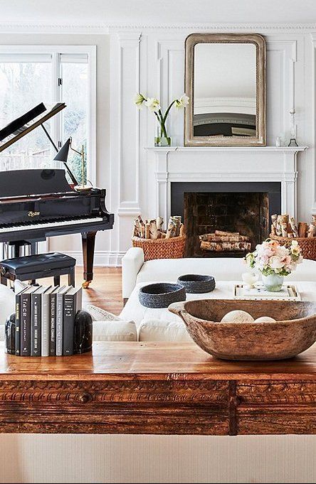 a living room filled with furniture and a piano in front of a fire place on top of a wooden table