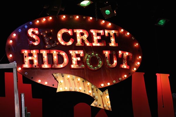 a sign that says s'cret hideout with lights around it and the words below it