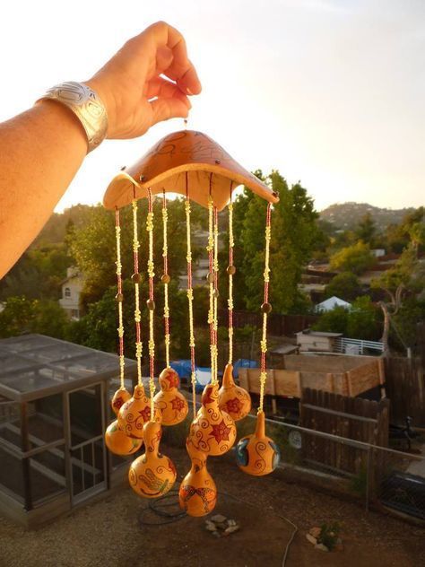 a person is holding up a wind chime with bells hanging from it's side