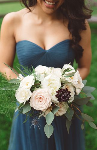 a woman in a blue dress holding a bouquet of white and pink flowers on her wedding day