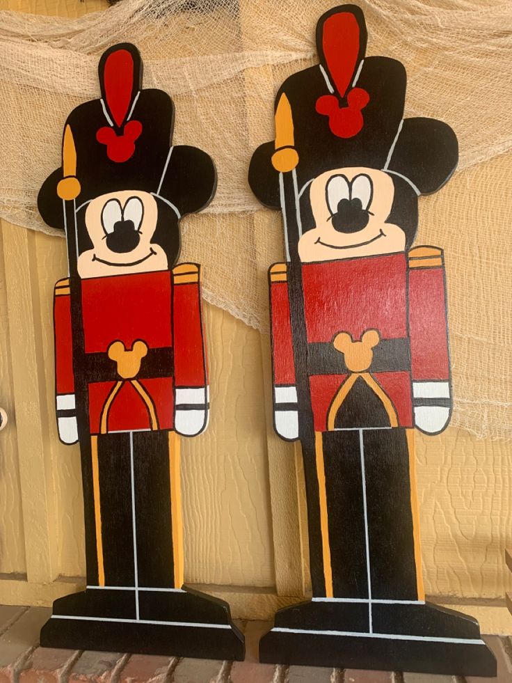 two wooden nutcrackers are decorated with red and black uniforms, one in the shape of mickey mouse