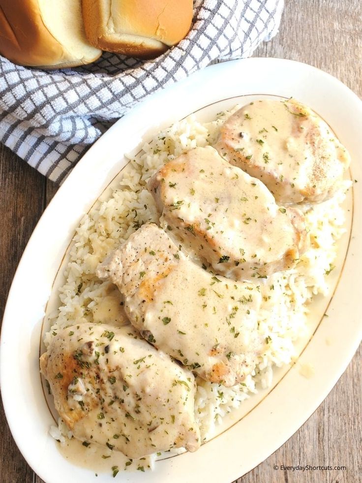 chicken with gravy and rice on a white plate next to a loaf of bread