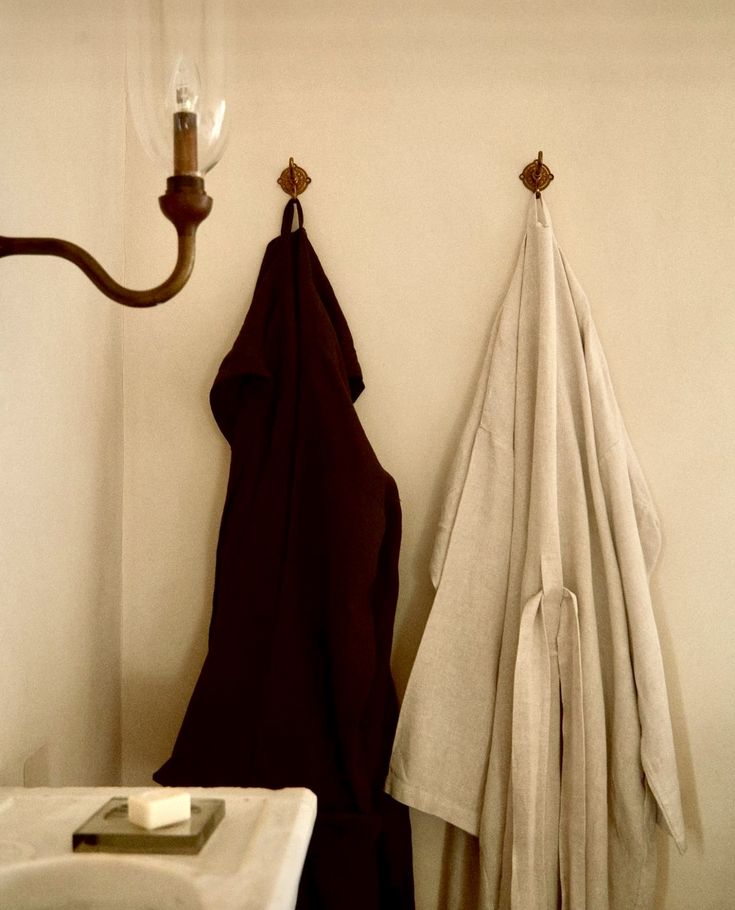 two towels hanging on the wall next to a towel rack and a light fixture in a bathroom