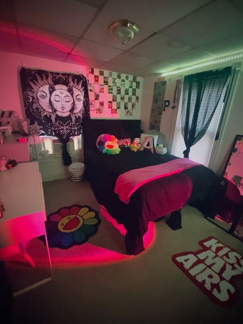 a bed room with a neatly made bed and pink lights on the wall above it