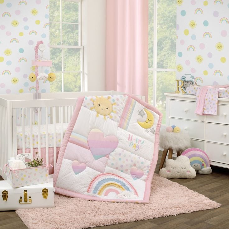 a baby crib with a teddy bear and rainbow quilt on the bed next to it