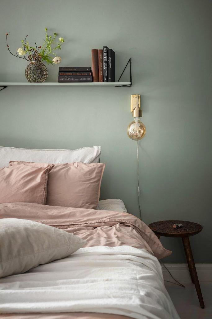 a bed with pink sheets and pillows on top of it next to a book shelf