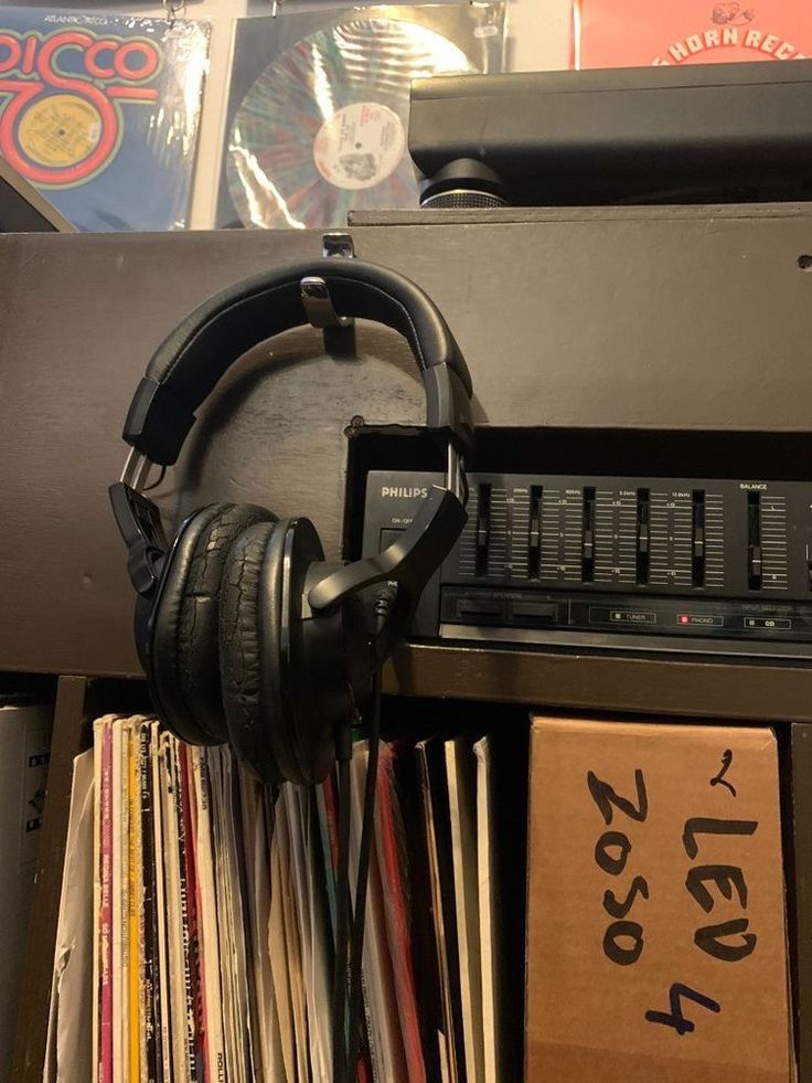 headphones on top of a record player in front of a shelf full of records