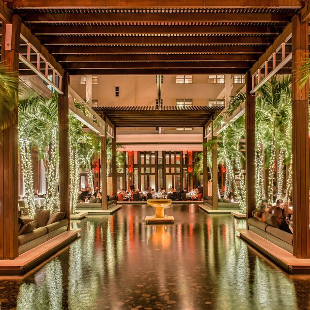 the inside of a hotel lobby with water reflecting on the floor and palm trees in the background