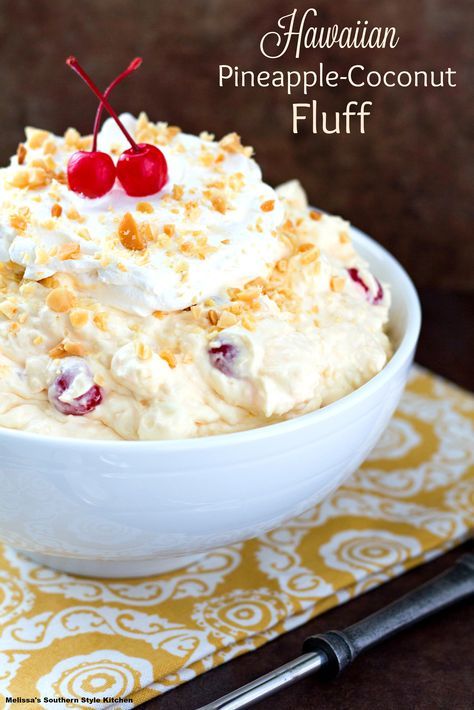 a bowl filled with fruit and whipped cream on top of a yellow place mat next to a fork