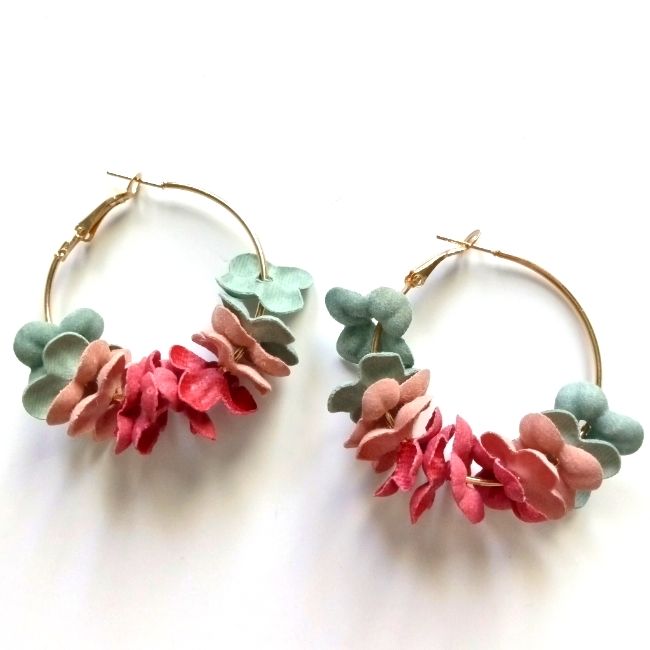 two pairs of hoop earrings with pink and green flowers on them, sitting side by side