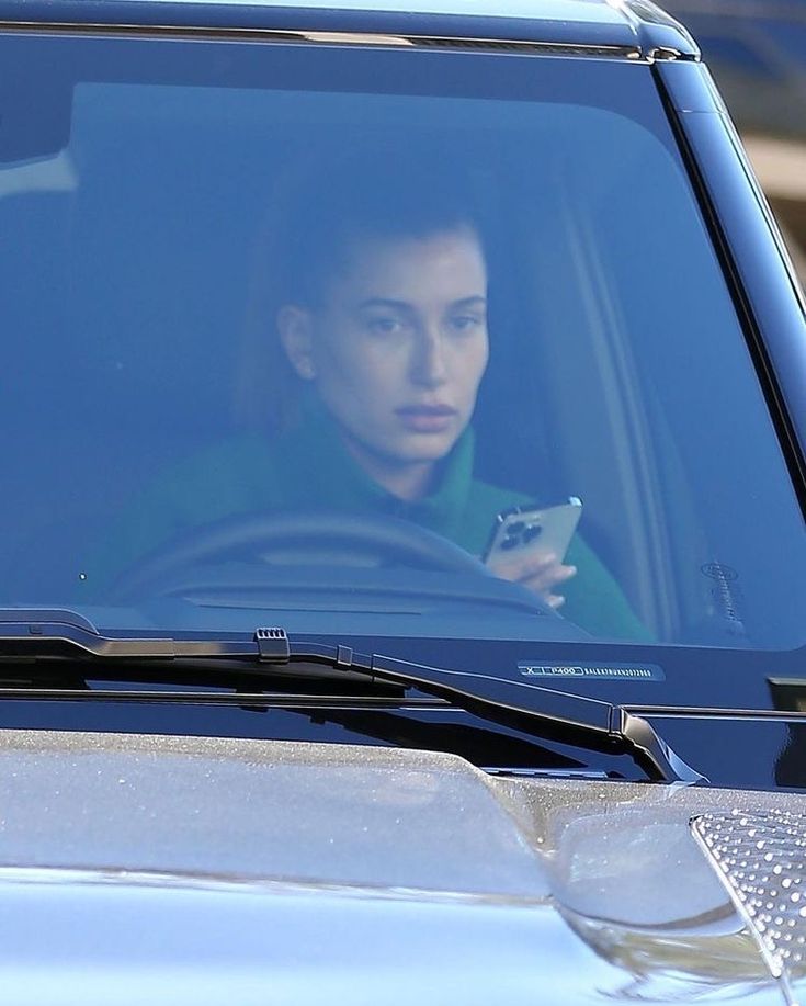 a woman sitting in the passenger seat of a car looking at her cell phone