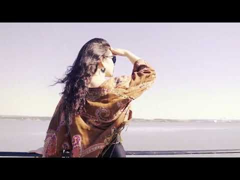 a woman standing on top of a beach next to the ocean with her hands in her hair