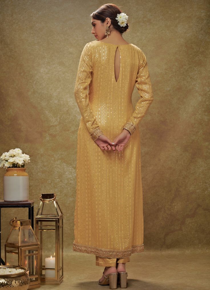 Introducing the elegant Champagne Gold Sequin Embroidered Kurta Pants Set, crafted from luxurious viscose georgette, this ensemble exudes sophistication and grace. The full-sleeved gold kurta is beautifully adorned with intricate sequin and thread embroidery, adding a touch of glamour to the look. Paired with straight-fit ankle-length pants, tailored silhouette that ensures both comfort and style. The ensemble is completed with a delicate net dupatta, featuring matching borders and scattered bootis, adding an ethereal charm. Perfect for Haldi, Mehndi, Sangeet, or as wedding guest attire, this outfit effortlessly combines traditional craftsmanship with contemporary elegance. Composition : Kurta - Viscose Georgette, Pants - Heavy Cotton Satin and Dupatta - Soft net Care: Dry Clean Only and V Gold Palazzo Set With Embroidery And Straight Kurta, Gold Palazzo Set With Straight Kurta And Gold Embroidery, Gold Sharara With Chikankari Embroidery, Traditional Long Sleeve Palazzo Set With Gold Embroidery, Embroidered Long Sleeve Salwar Kameez For Reception, Festive Long Sleeve Palazzo Set With Gold Embroidery, Gold Straight Kurta Palazzo Set For Reception, Gold Palazzo Set With Straight Kurta For Reception, Gold Palazzo Set With Resham Embroidery, Floor-length