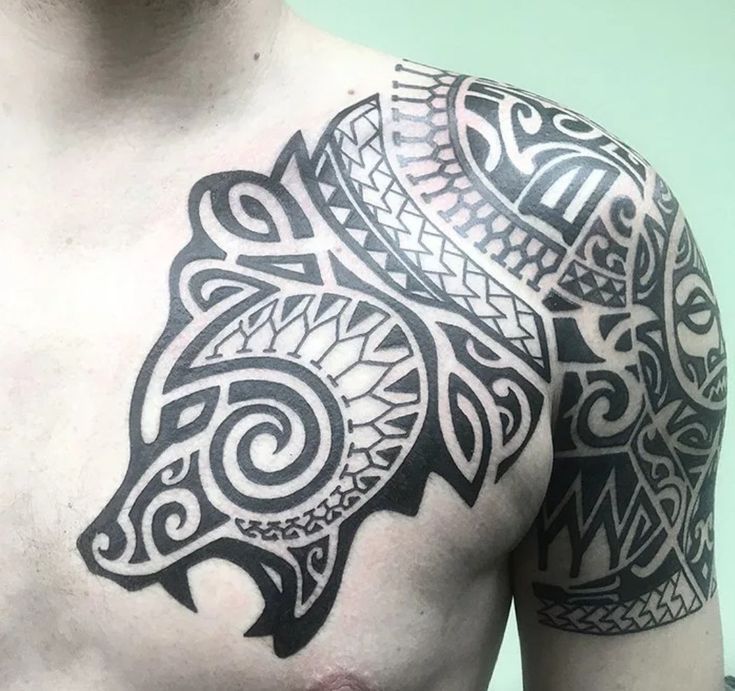 a man's chest with an intricate tattoo design on his left arm and shoulder