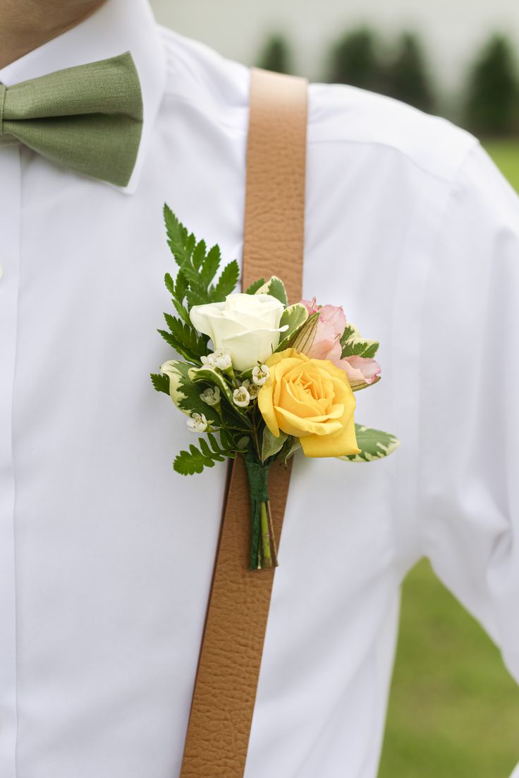 Groomsman or groom wearing colorful boutonniere of yellow white and blush roses with tan suspenders, white shirt and sage green bowtie Yellow And Pink Corsage, Yellow Rose Corsage, Bright Yellow Wedding, Pink Groomsmen, Yellow Boutonniere, Groomsman Boutonniere, Pink Boutonniere, Prom Corsage And Boutonniere, Yellow Carnations