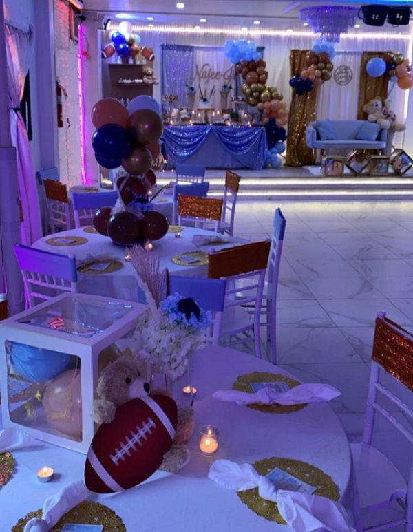 a room filled with tables and chairs covered in white tablecloths, balloons and decorations