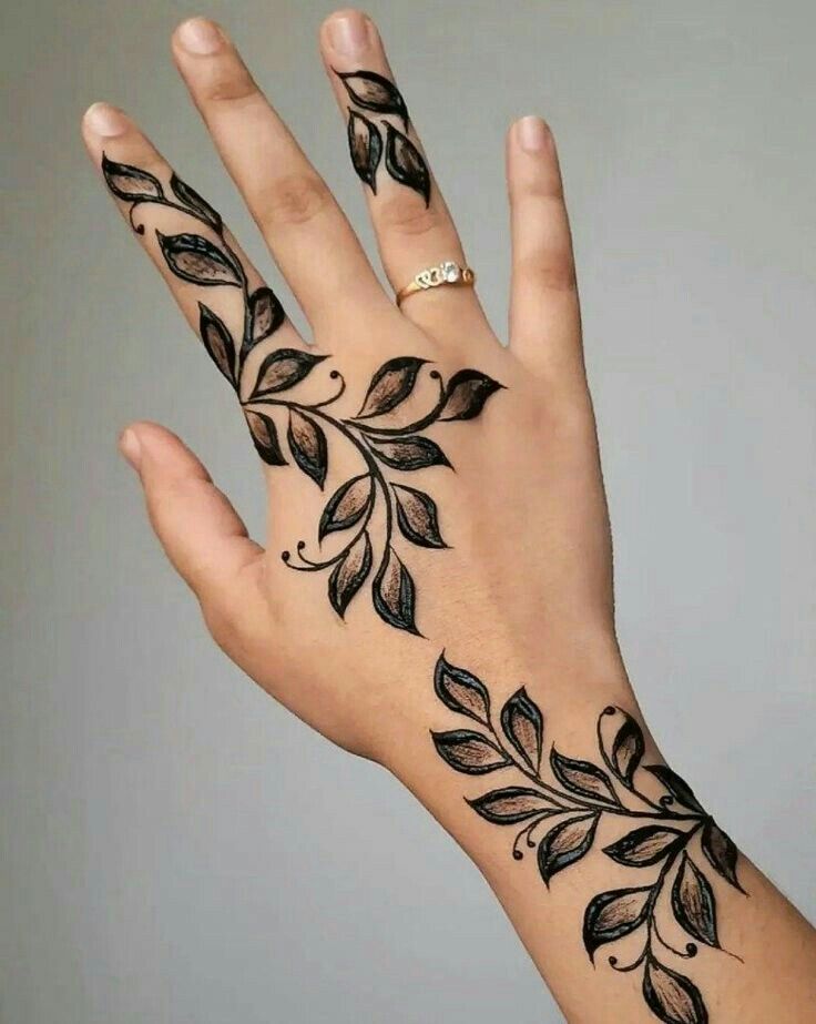 a woman's hand with black leaves on it