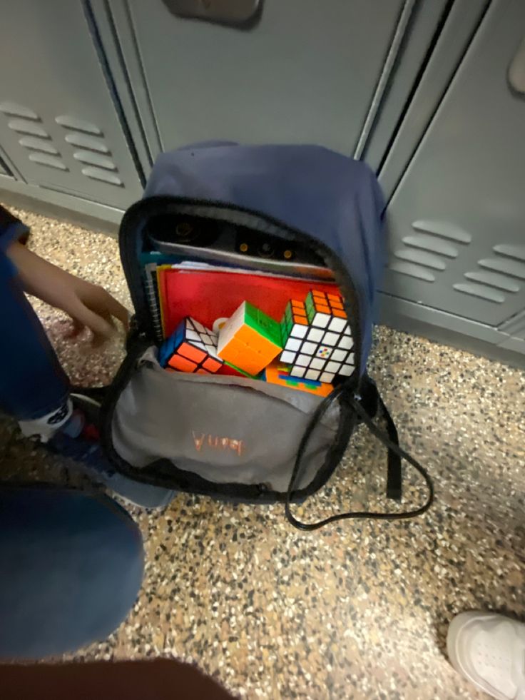 someone is sitting on the floor with their back pack full of books and magazines in front of them