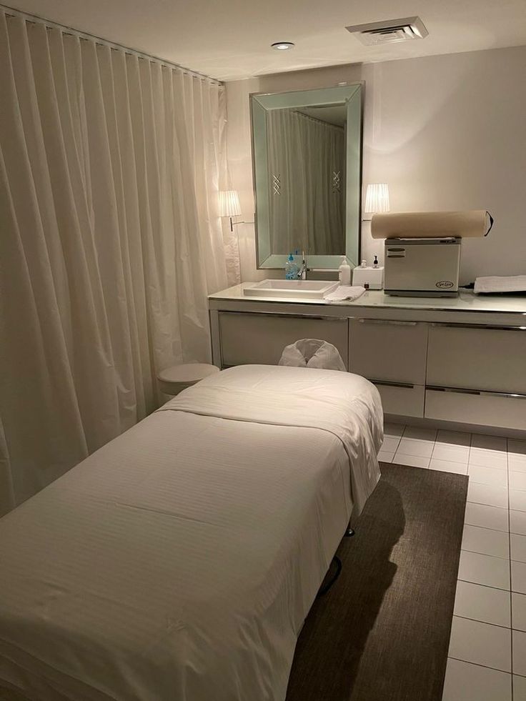 two beds in a room with white tile flooring and wall mounted mirrors above them