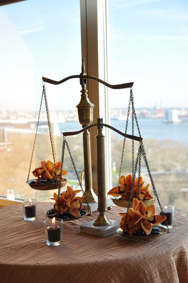 a scale with flowers and candles on it in front of a window overlooking the water