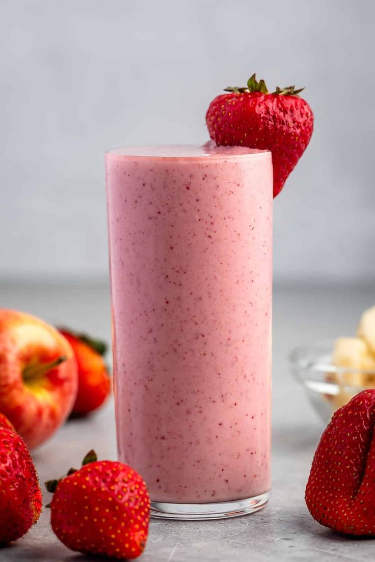 a smoothie in a glass with strawberries on the side