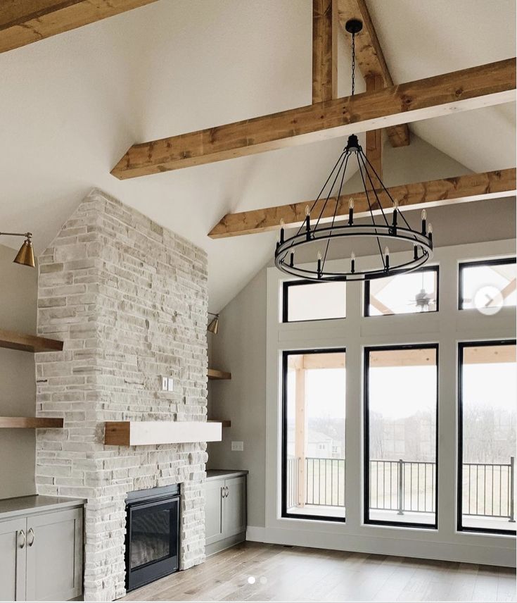 an empty living room with large windows and wood beams on the ceiling is pictured in this image