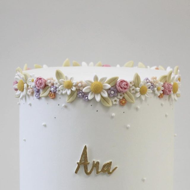 there is a white cake with flowers on the top and an am written in gold