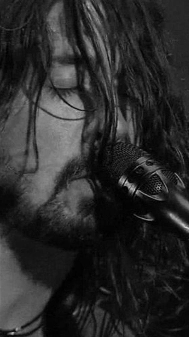 a man with long hair is singing into a microphone