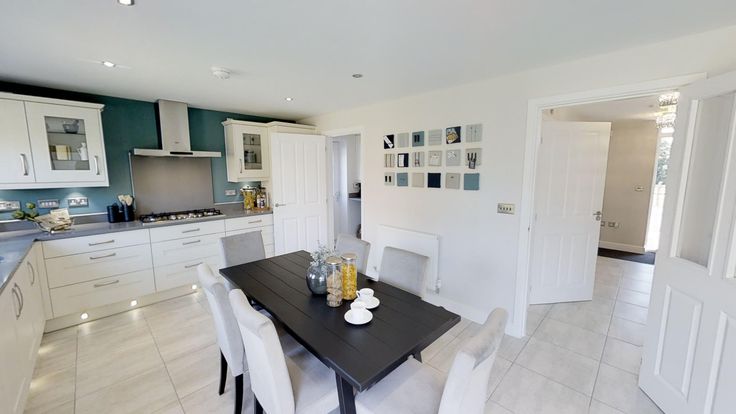 a dining room and kitchen area in a home with white cabinets, black table and chairs