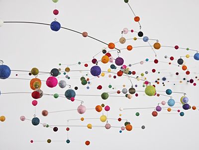 multicolored balls are hanging from the ceiling in an art installation with white background