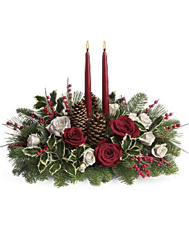 a christmas centerpiece with red candles and greenery in the center, surrounded by white roses